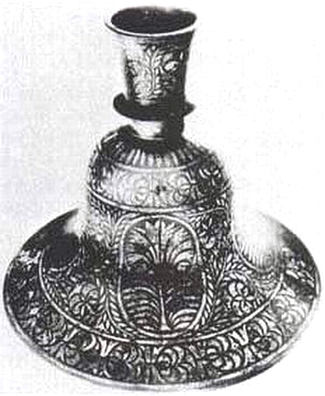 Взрыв вынес на поверхность две половинки предмета, названного «колоколом». Его высота составляет 12 см, толщина стенок из металлического сплава – 0,3 см. На поверхности (диаметр «колокола» 16,5 см) серебром выложены аппликации в виде веночка и шести цветков. Ни эта находка, ни подобные ей не находят объяснения до сих пор относительно назначения, происхождения и производства.